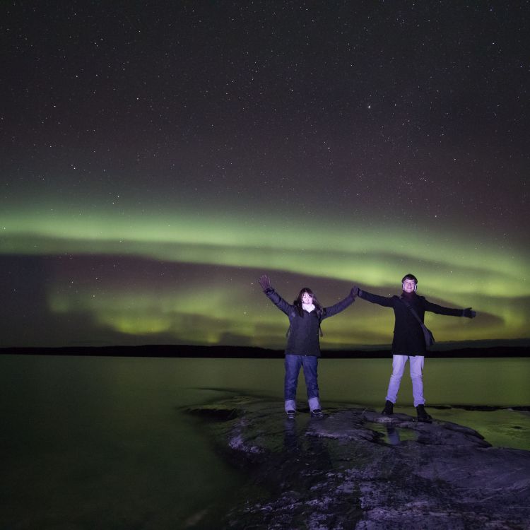 Two people having fun under the aurora / northern lights